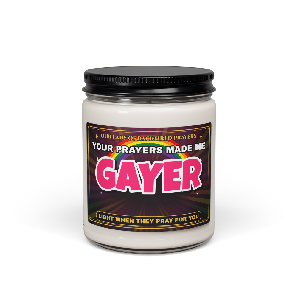 Nice Gay 9 oz soy candle in a clear glass jar with a black lid, front view, with a label reading "Our Lady of Backfired Prayers," "Your Prayers Made Me GAYER," and "Light when they pray for you" over a rainbow.