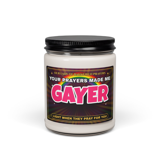 Nice Gay 9 oz soy candle in a clear glass jar with a black lid, front view, with a label reading "Our Lady of Backfired Prayers," "Your Prayers Made Me GAYER," and "Light when they pray for you" over a rainbow.