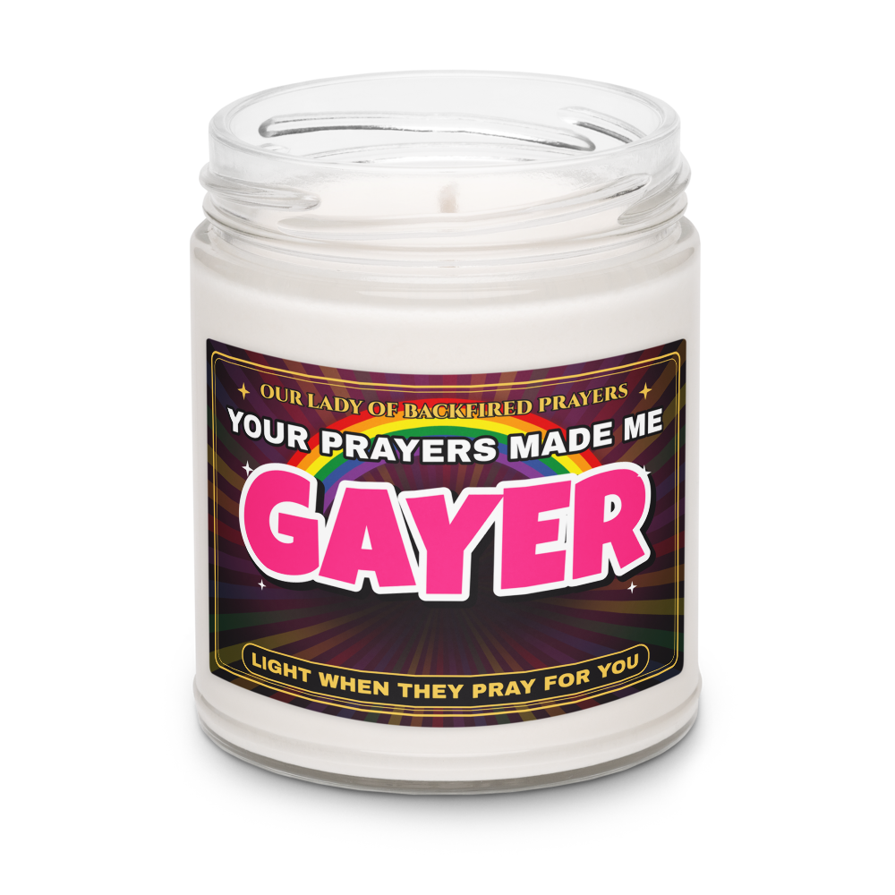 Close-up of the Nice Gay soy candle with the lid off, showing the label reading "Our Lady of Backfired Prayers," "Your Prayers Made Me GAYER," and "Light when they pray for you."